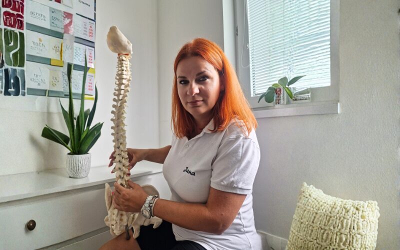 Fyzioterapeutka Janka drží model ľudskej chrbtice v ambulancii.